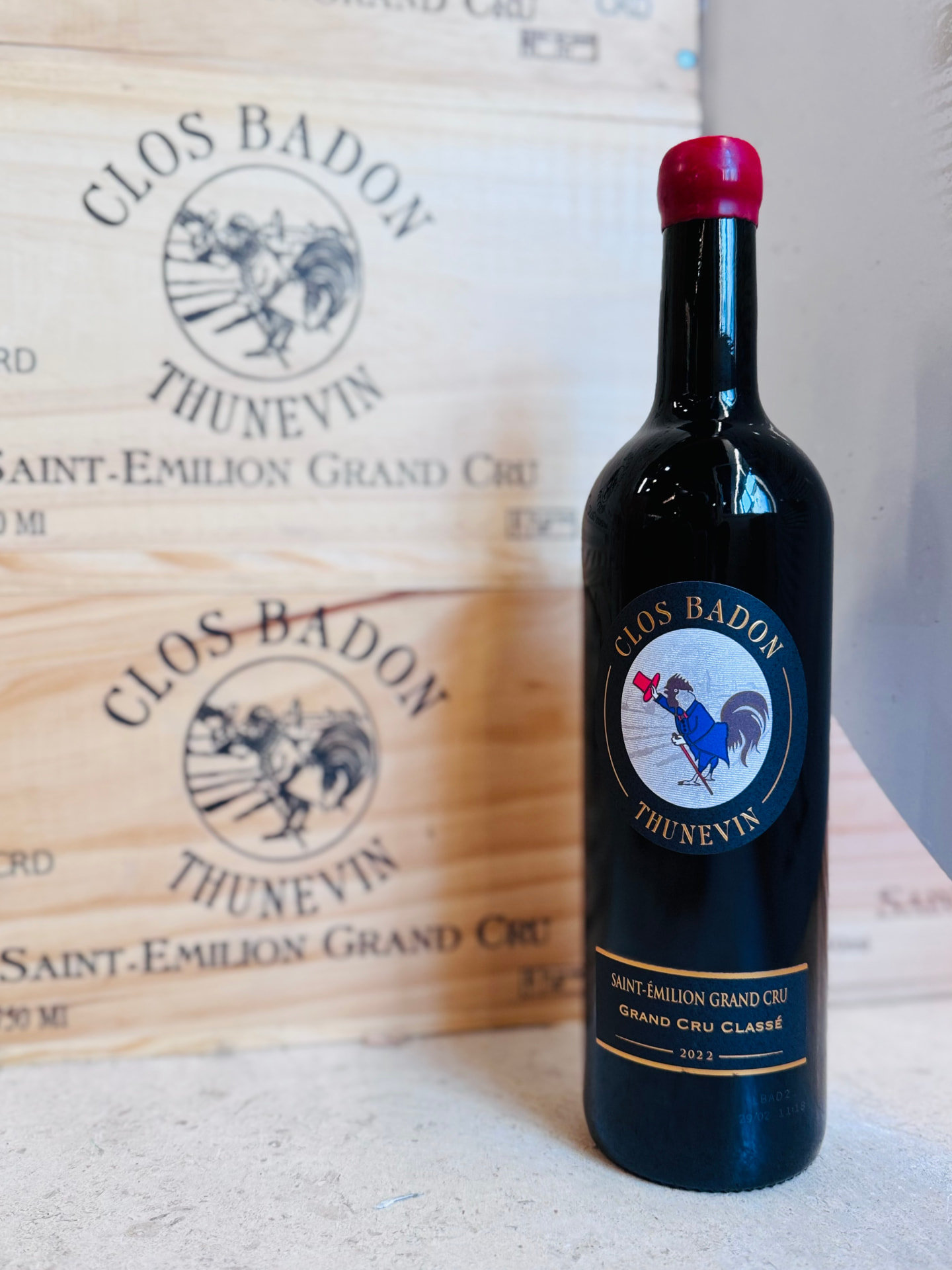 Bouteille de Clos Badon-Thunevin millésime 2022 devant des caisses en bois du domaine